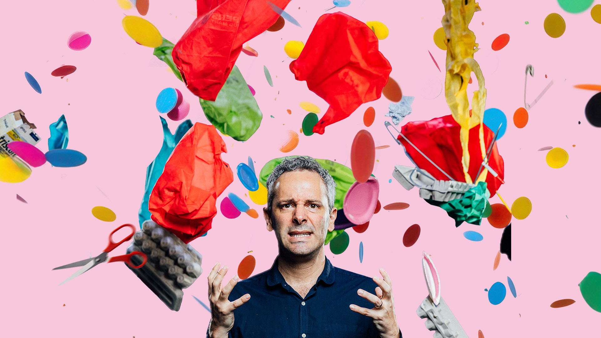 Adam looking stressed with his hands in front of him as bags, egg cartons, markers, and other junks flies through the sky around him.